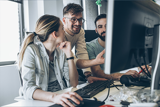 Drei Menschen sitzen vor einem PC Bildschirm