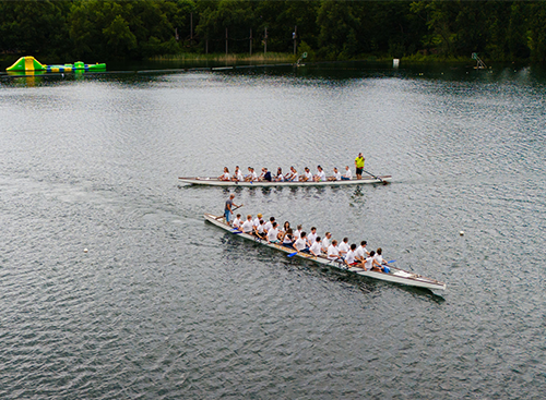 Zwei Drachenboote auf dem Wasser mit Menschen an Bord